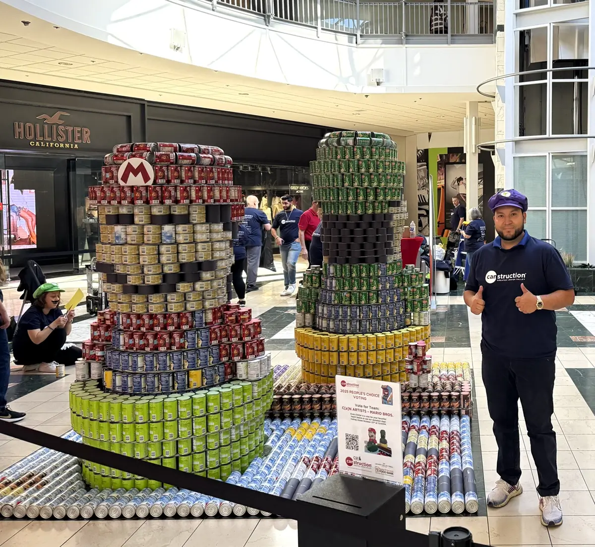 Diego X. Eras, PE posing with the Super Mario–inspired CANstruction sculpture made from 3,400 cans for the 2025 “GAME ON!” themed event